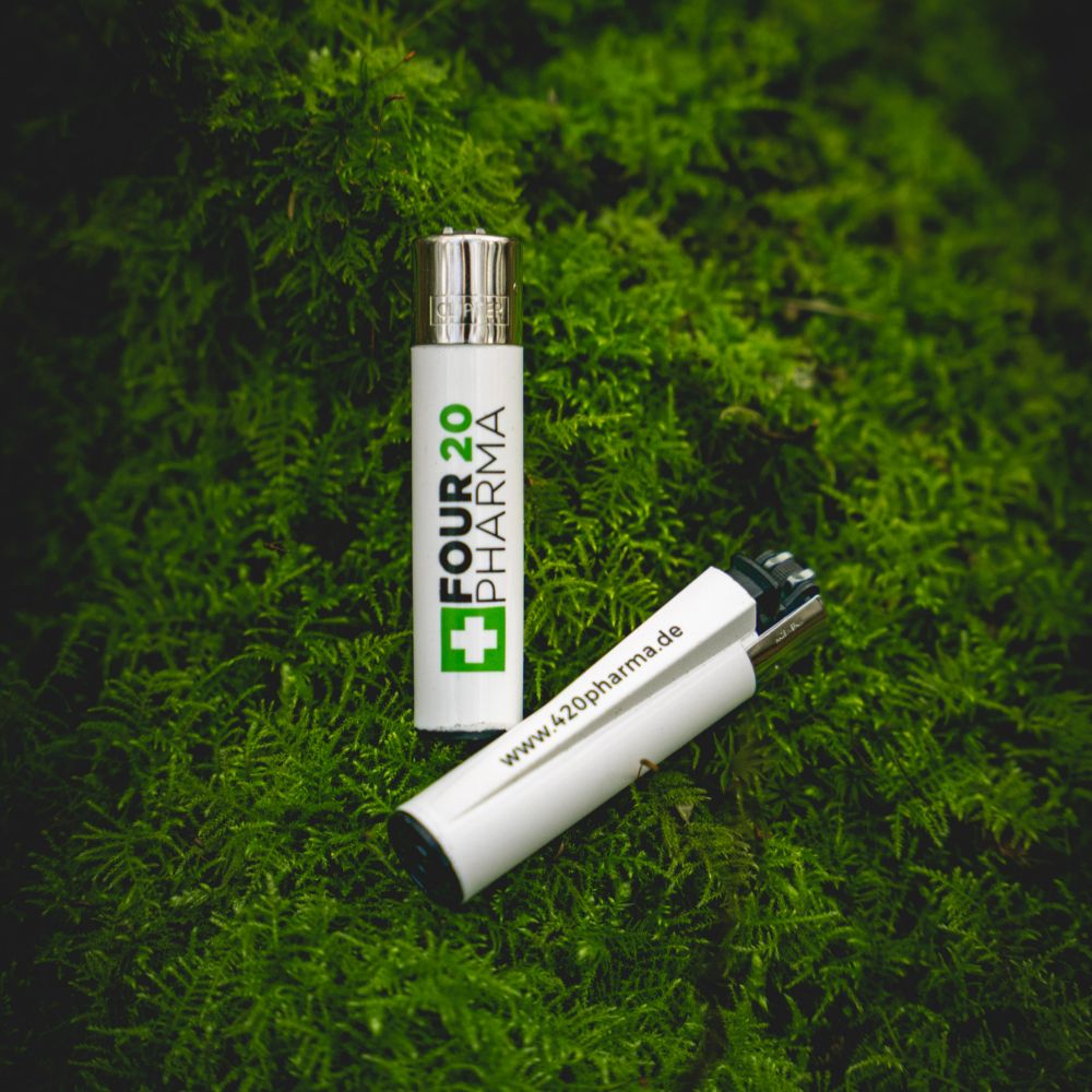 Four 20 Pharma Clipper Feuerzeug auf Walduntergrund