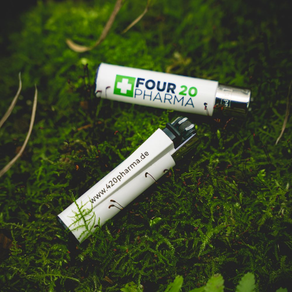 Four 20 Pharma Clipper Feuerzeug auf Walduntergrund