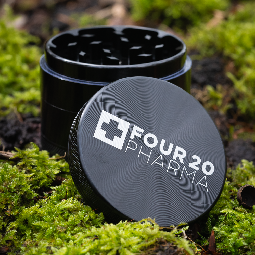 Four 20 Pharma Alu Grinder schwarz mit Waldhintergrund Nahaufnahme
