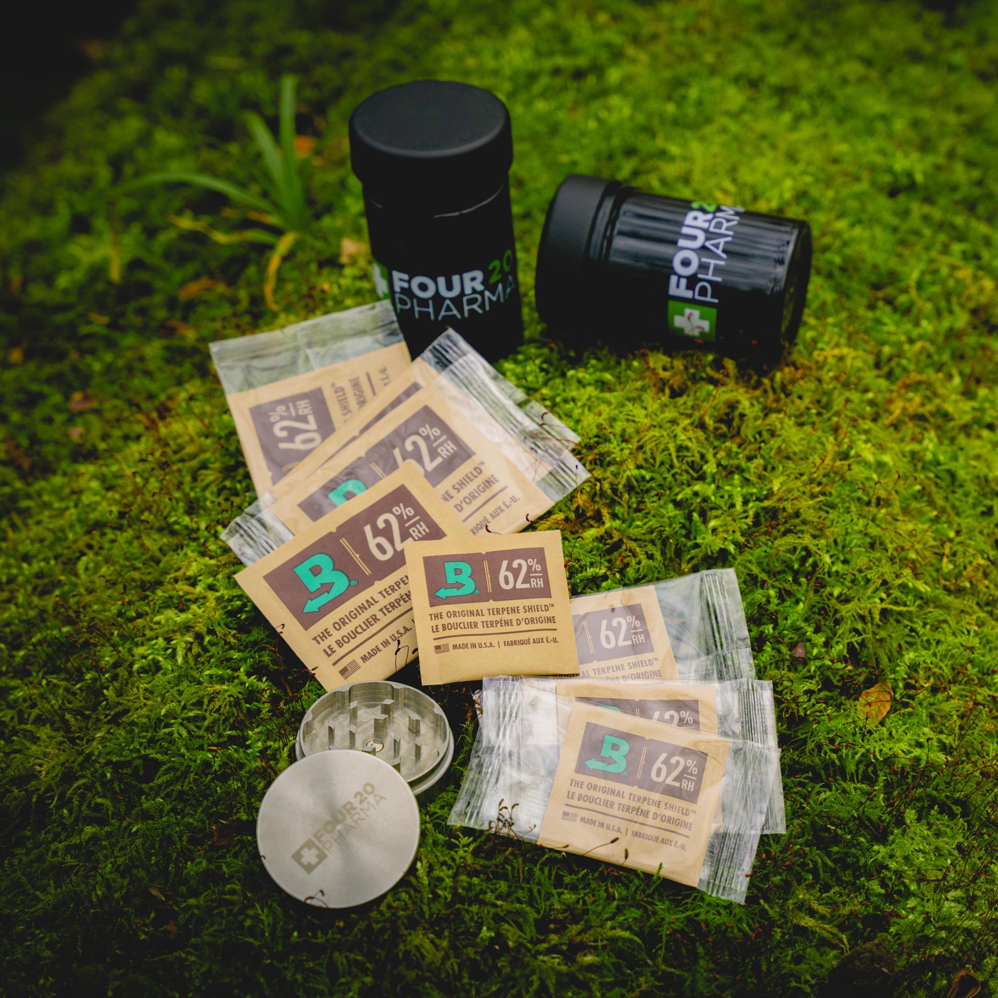 Four 20 Pharma Blütendose, Boveda Terpene Shield und Grinder auf Moos Untergrund 