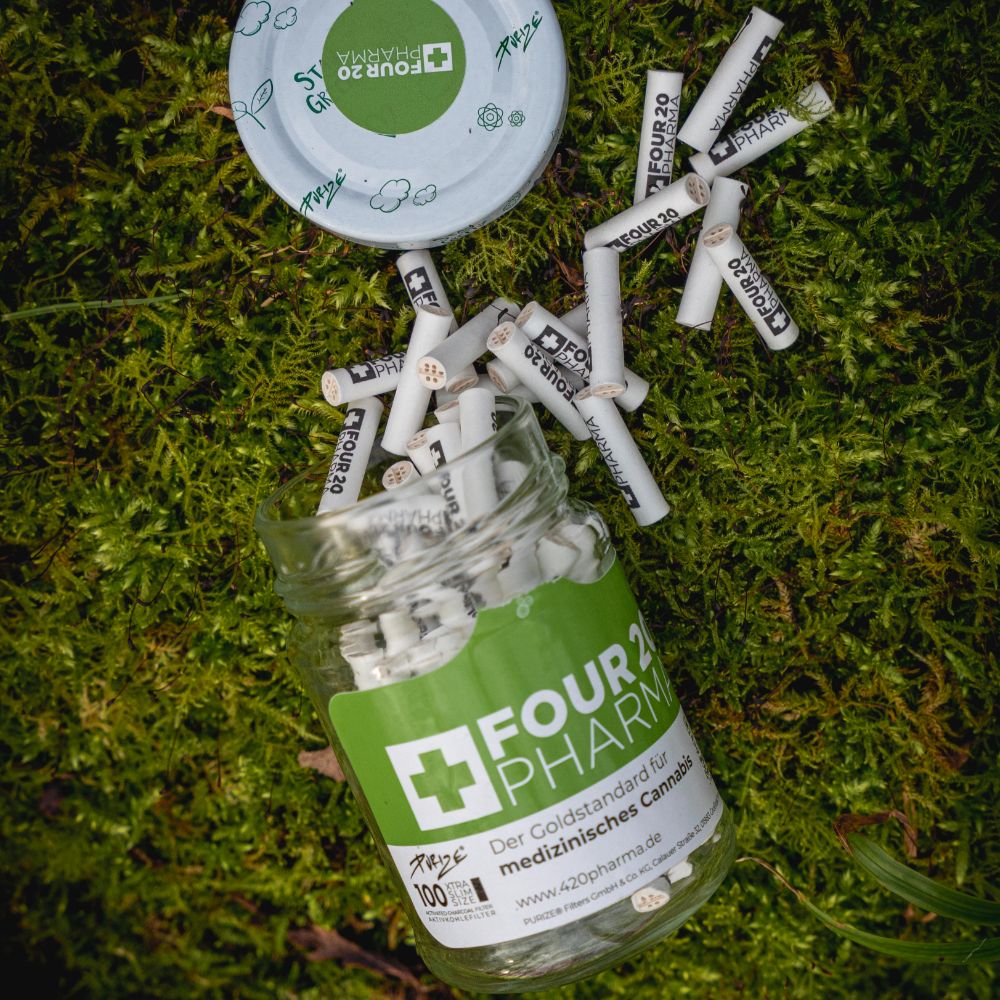 Four 20 Pharma Aktivkohlefilter im Glas auf Walduntergrund